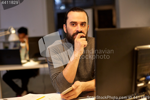 Image of creative man with computer working at night office