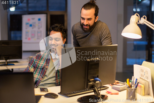 Image of creative team with computer working late at office