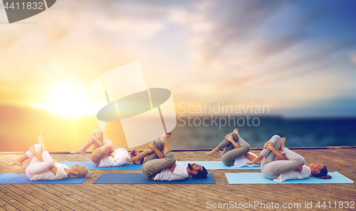 Image of group of people doing yoga pose outdoors