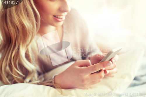Image of close up of woman with smartphone in bed at home