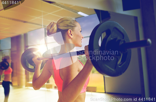 Image of sporty woman exercising with barbell in gym