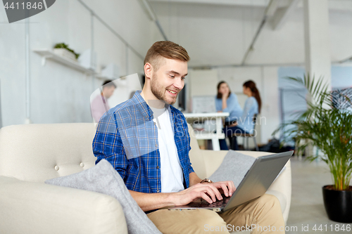 Image of smiling man with laptop working at office