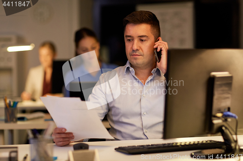 Image of businessman calling on sartphone at night office