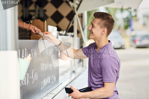 Image of happy young man paying money at food truck