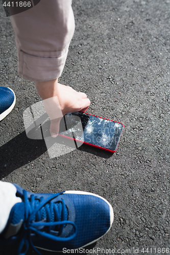 Image of Woman raises from the ground a broken smartphone