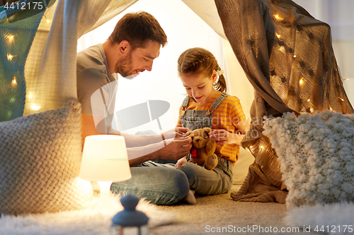 Image of happy family playing with toy in kids tent at home