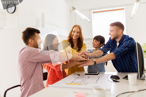 Image of creative team holding hands together at office