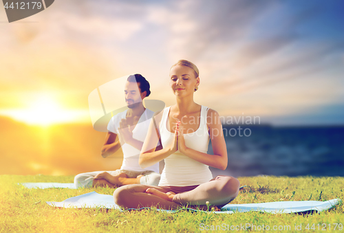 Image of happy couple making yoga and meditating outdoors