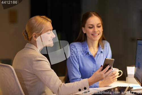 Image of businesswomen with smartphone late at night office