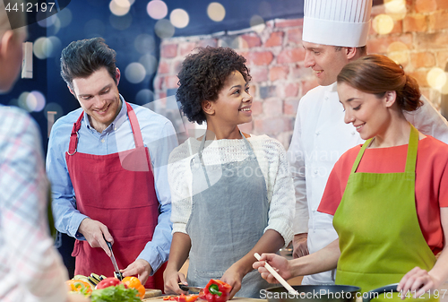 Image of happy friends and chef cook cooking in kitchen