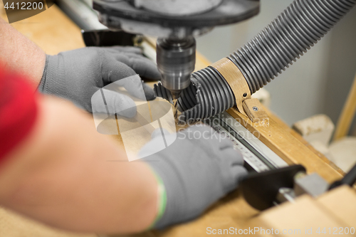 Image of carpenter with drill press and board at workshop