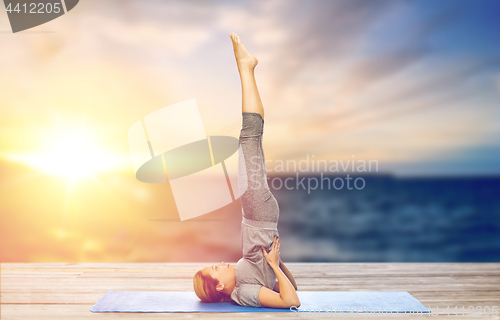 Image of woman doing yoga in shoulderstand pose on mat