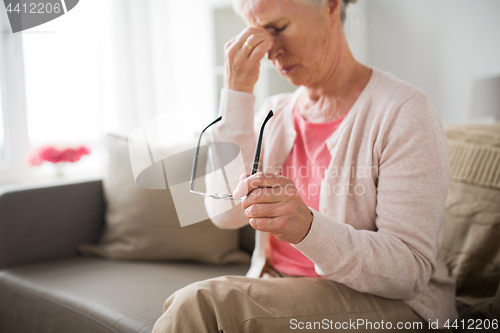 Image of senior woman with glasses having headache at home