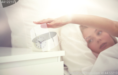 Image of close up of woman with alarm clock in bed at home