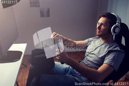 Image of man playing car racing video game at home