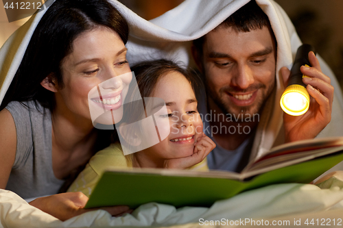 Image of happy family reading book in bed at night at home