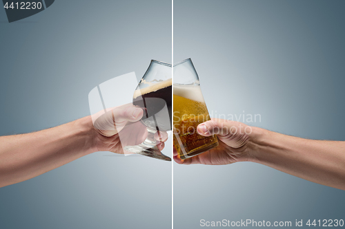 Image of Closeup of a male hand holding up a glass of beer