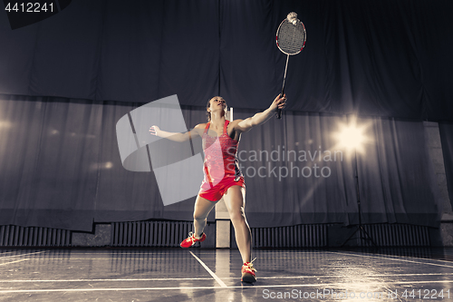 Image of Young woman playing badminton at gym