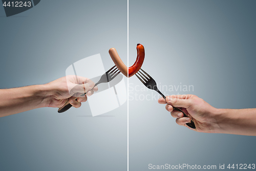Image of sausage on a fork in his hand