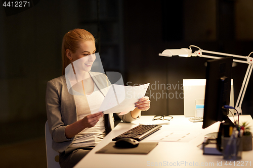 Image of businesswoman with papers working at night office