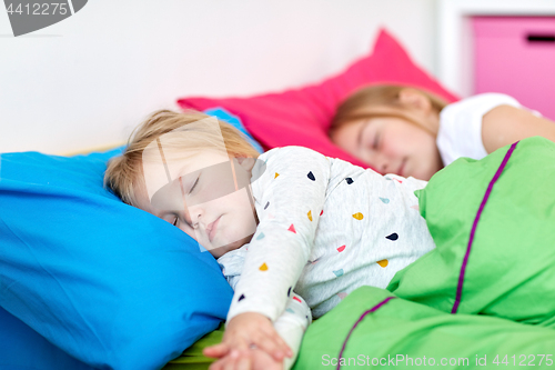 Image of happy little girls sleeping in bed at home