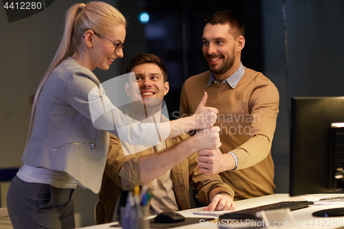 Image of business team making thumbs up gesture at office