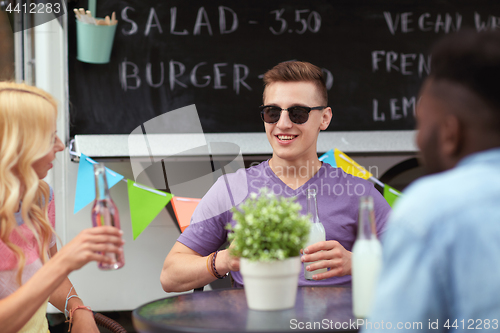 Image of friends with drinks sitting at table at food truck