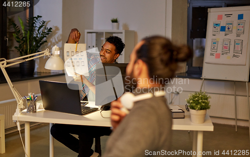 Image of creative man showing papers to colleague at office