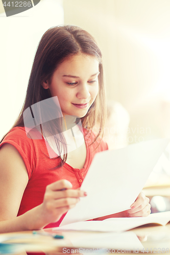 Image of happy student girl with test paper at school