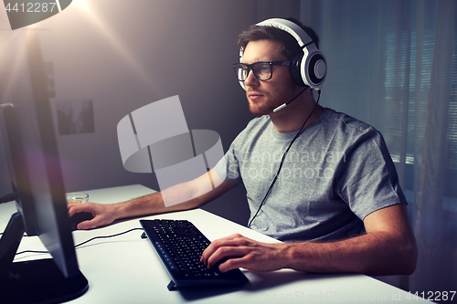 Image of man in headset playing computer video game at home