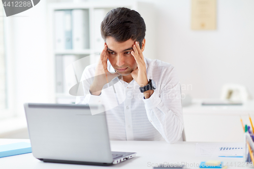 Image of stressed businessman with laptop at office