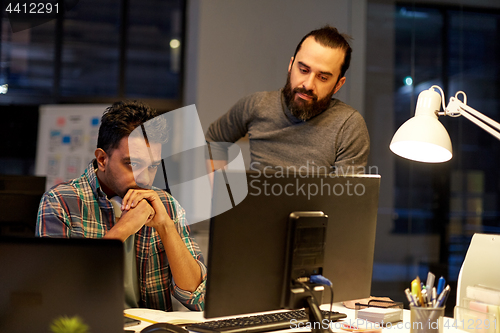 Image of creative team with computer working late at office