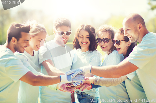 Image of group of volunteers putting hands on top in park