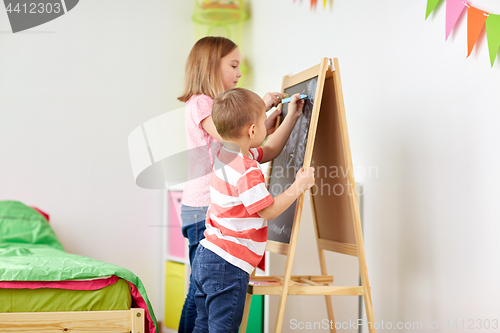 Image of happy kids drawing on chalk board at home