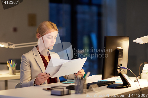 Image of businesswoman with papers working at night office