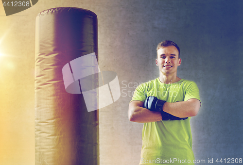 Image of man with boxing gloves and punching bag in gym