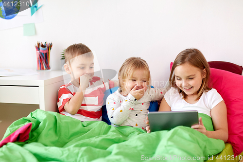 Image of little kids with tablet pc in bed at home