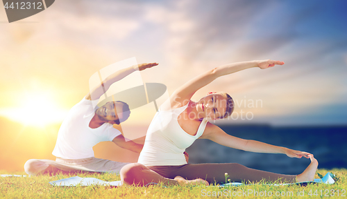 Image of couple making yoga exercises outdoors