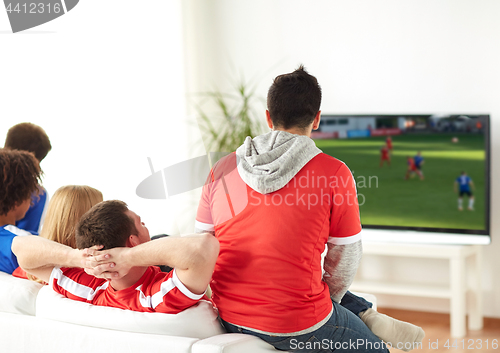 Image of football fans watching soccer game on tv at home