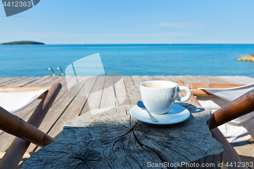 Image of Wooden floor and sea view with chaise-longues and coffee