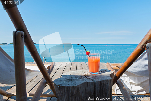 Image of Wooden floor and sea view with chaise-longues and cocktail