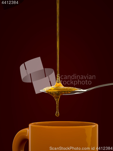 Image of a spoon full of golden honey over a tea mug