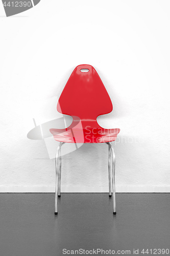 Image of empty red chair at a white wall