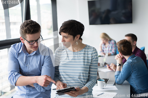 Image of Two Business People Working With Tablet in office