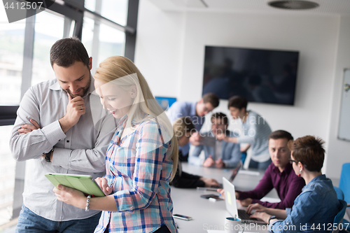 Image of Two Business People Working With Tablet in office