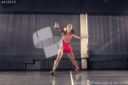 Image of Young woman playing badminton at gym