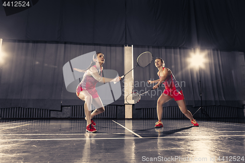 Image of Young women playing badminton at gym