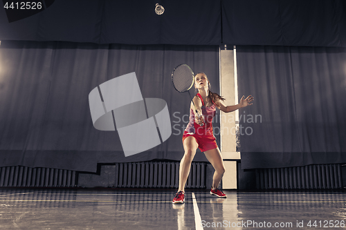 Image of Young woman playing badminton at gym