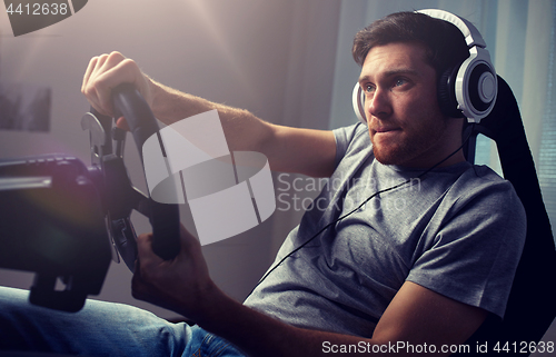 Image of man playing car racing video game at home