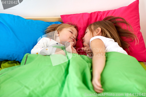 Image of happy little girls sleeping in bed at home